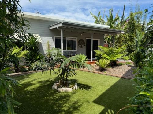 a house with a grass yard with a palm tree at Shoaly House and Shoaly House Cottage - perfect for multiple families & wedding groups in Shoal Bay