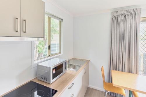 a kitchen with a sink and a microwave on a counter at RAC Busselton Holiday Park in Busselton