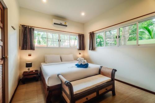 een slaapkamer met een bed met een bank en ramen bij Chaba Pool Villa in Nai Harn Beach