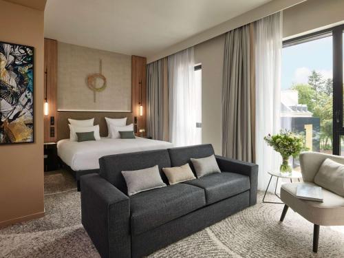 a hotel room with a bed and a couch at Domaine du Liziec Vannes - MGallery Collection in Vannes