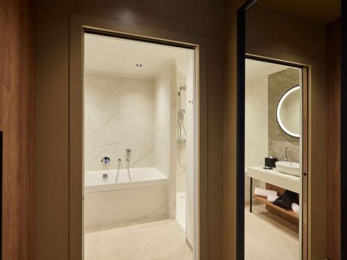 a bathroom with a bath tub and a sink at Domaine du Liziec Vannes - MGallery Collection in Vannes