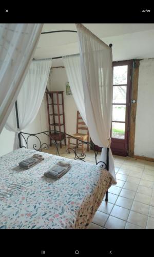 a bedroom with a bed with curtains and a window at Chambres dans gîte campagnard in Mers-sur-Indre