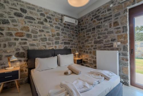 a bedroom with a bed and a stone wall at Villa Liatiko with private pool in Atsipádhes