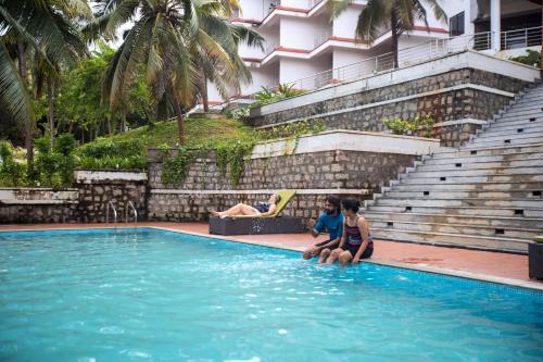 two children sitting in the water in a swimming pool at EZHIMALA AYURVEDA AND WELLNESS RESORT in Payyannūr