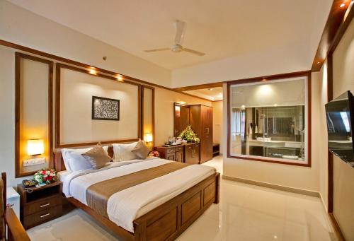 a bedroom with a large bed and a television at EZHIMALA AYURVEDA AND WELLNESS RESORT in Payyannūr