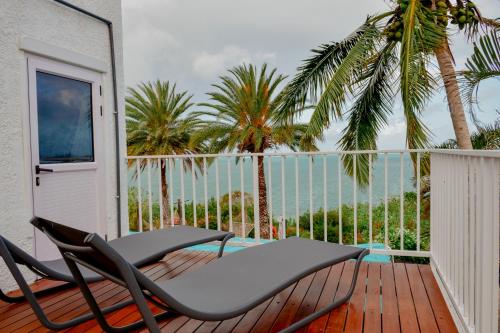a balcony with two chairs and palm trees at Boutique Villa on the Rocks with Stunning Sea Views, Infinity Pool & Private Sea in Trou dʼ Eau Douce