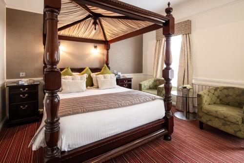セント・ヘリア・ジャージーにあるBest Western Royal Hotelのベッドルーム(天蓋付きベッド1台、椅子付)