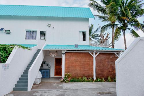 a white house with a blue roof and a staircase at Boutique Villa on the Rocks with Stunning Sea Views, Infinity Pool & Private Sea in Trou dʼ Eau Douce