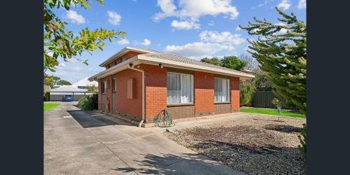 a small red brick house on a driveway at Holiday Rentals in Ascot Park