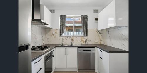 a white kitchen with white cabinets and a window at Holiday Rentals in Ascot Park