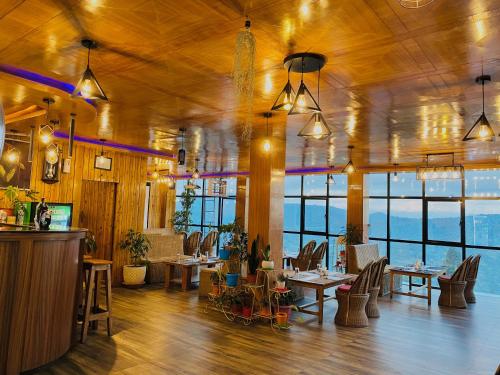 a restaurant with tables and chairs and windows at Easton Blue Hotel in Ilām