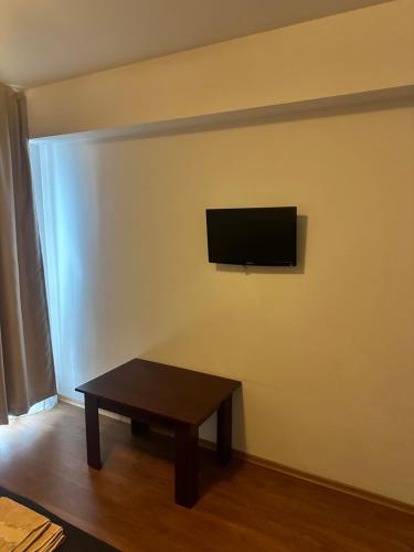 a living room with a table and a tv on a wall at Pensiunea Artemis in Craiova
