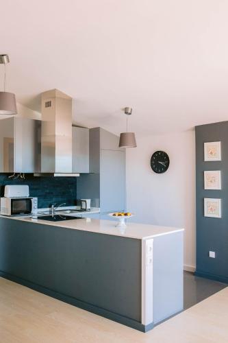 a kitchen with a counter and a clock on the wall at Viana Rooftop House - Apartment in the historic center with river view in Viana do Castelo