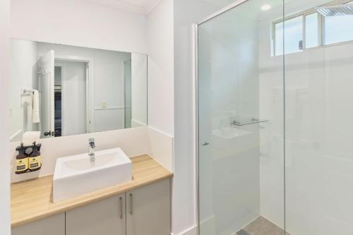 a white bathroom with a sink and a shower at RAC Busselton Holiday Park in Busselton