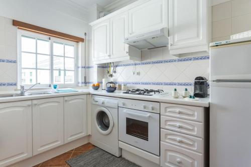 a kitchen with white cabinets and a washer and dryer at Beachside Golf and City Escape by Lisbeyond in Tavira
