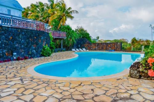 a swimming pool in a yard with a stone wall at Boutique Villa on the Rocks with Stunning Sea Views, Infinity Pool & Private Sea in Trou dʼ Eau Douce