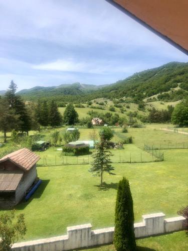 a view of a field with a house and mountains at Hotel Bucaneve in Pescasseroli