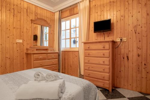 Un dormitorio con una cama y una cómoda con televisión. en Casa Bambury, en Conil de la Frontera