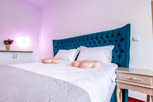 a bedroom with a large bed with a blue headboard at Boutique Boema in Târgovişte