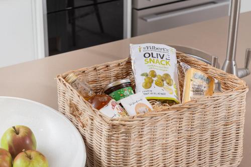 a basket of food and drinks on a table with a plate at Spacious House in the Heart of Cheddar in Cheddar