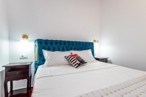 a bed with a blue headboard and two pillows on it at Boutique Boema in Târgovişte