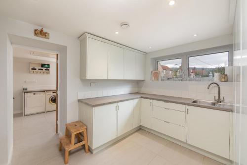 a kitchen with white cabinets and a sink and a window at Spacious House in the Heart of Cheddar in Cheddar