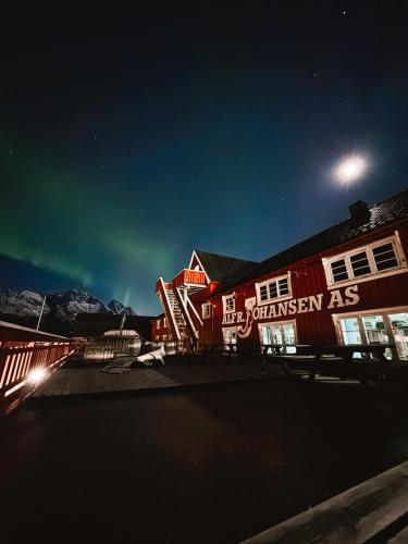 a red building with a sign on it at night at Finnholmen Brygge in Henningsvær