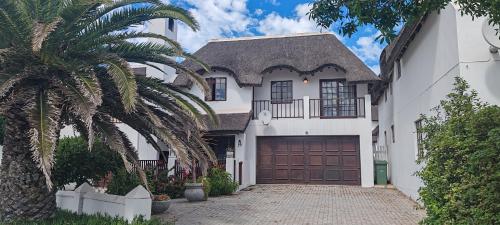 a white house with a garage and a palm tree at Concha at Shelley Point in Stompneusbaai