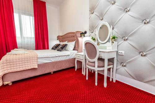 a bedroom with a bed and a table with a mirror at Boutique Boema in Târgovişte