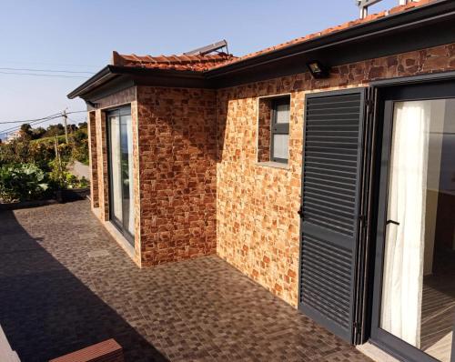 a brick house with a black garage at Villa do Italiane in Estreito da Calheta