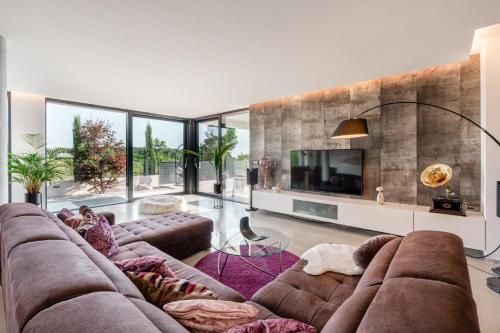 un salon avec un grand canapé et une télévision dans l'établissement Villa Aria Višnjan near Poreč for 12 people - pet friendly with wellness & sea view, à Višnjan