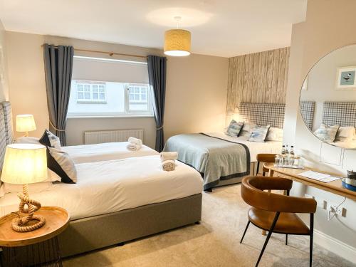 a hotel room with two beds and a desk at Beach House Hotel in Seahouses