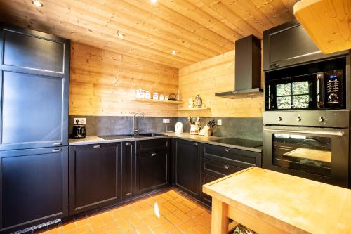 d'une cuisine avec des armoires noires et un plafond en bois. dans l'établissement CHALET SPA BELLE VUE 500 m des pistes, à Manigod