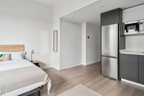 a bedroom with a bed and a refrigerator at Truliving Vallecas by Habyt in Vallecas