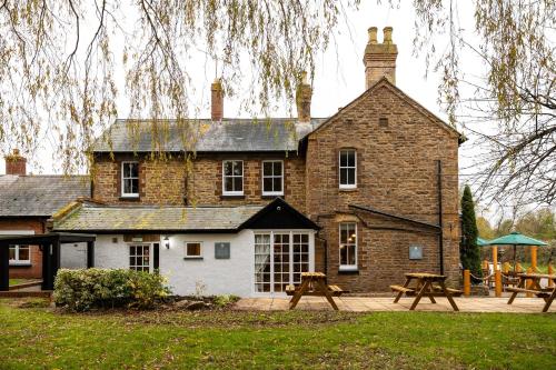 a large brick building with picnic tables in front of it at The Olde Coach House Inn in Ashby Saint Ledgers