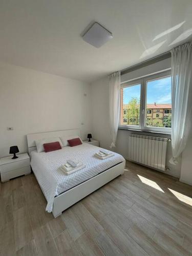 a white bedroom with a bed and a large window at Appartamento vicino a Como in Mozzate
