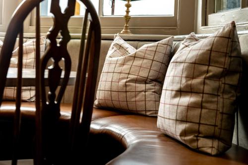 a group of pillows on a couch with a window at The Olde Coach House Inn in Ashby Saint Ledgers