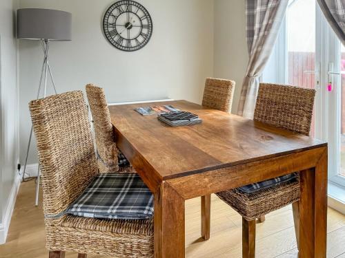 a dining room table with chairs and a clock on the wall at House In The Highlands in Fort William
