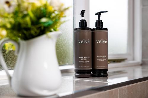 two bottles of hair products on a counter with a vase at The Olde Coach House Inn in Ashby Saint Ledgers