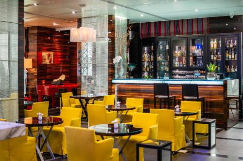a restaurant with yellow chairs and tables and a bar at ROMEO Napoli in Naples