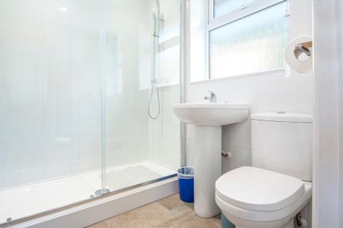 a white bathroom with a toilet and a shower at Agos Y Mor in Haverfordwest