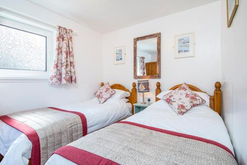 two beds in a room with a mirror and a window at Agos Y Mor in Haverfordwest