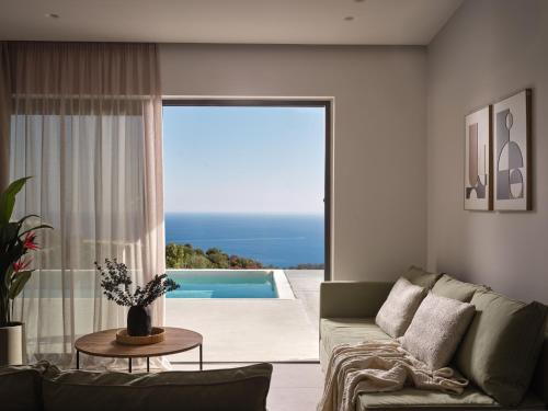 a living room with a couch and a view of a pool at Askos Luxury Suites, a Zakynthian Hideaway, By ThinkVilla in Agios Nikolaos