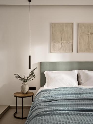 a bedroom with a bed and a vase on a table at Askos Luxury Suites, a Zakynthian Hideaway, By ThinkVilla in Agios Nikolaos