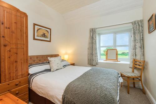 Un dormitorio con una cama y una ventana y una silla. en Felin Fach, en Haverfordwest