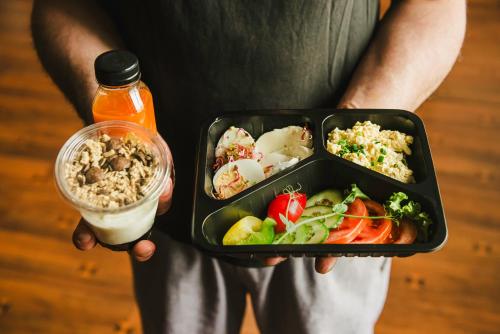 eine Person, die ein Tablett mit Essen und einem Getränk hält in der Unterkunft Triton Apartments in Warschau