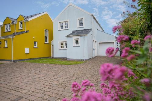 ein Haus mit gelben und weißen Gebäuden und rosa Blumen in der Unterkunft 3 Stable Yard in St. Davids