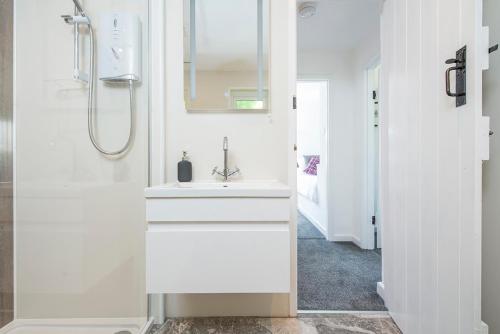 ein weißes Badezimmer mit Waschbecken und Dusche in der Unterkunft Ty Olwen in Haverfordwest