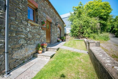 a stone house with a stone wall and a yard at The Cart House in Haverfordwest