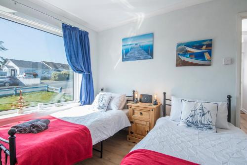 Un dormitorio con dos camas y una gran ventana. en Sandgrove, en Saundersfoot